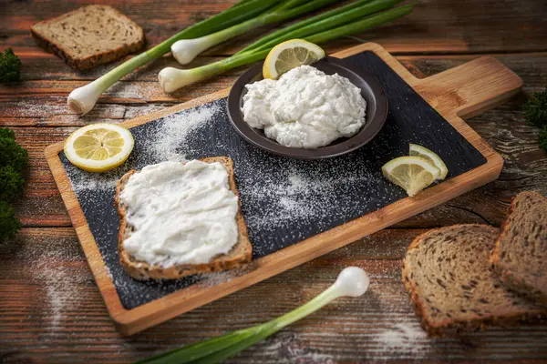 Lezzetli ev yapımı balık yumurtası ekmek ve taze soğanla sade ahşap masaya yayılmış.