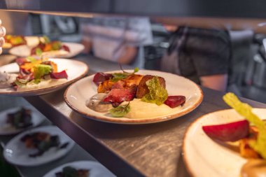 Lokanta mutfağında servis edilmeyi bekleyen lezzetli et ve sebzelerle dolu tabaklar.