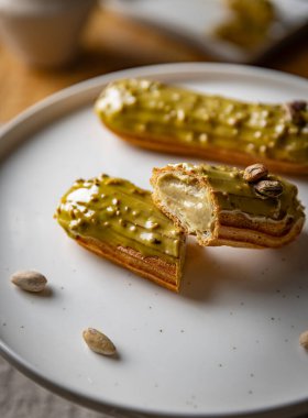 Pistachio eclairs with light green icing resting on white  plate clipart