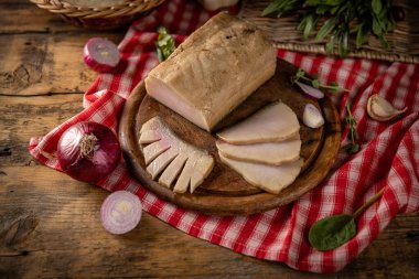 Ağaç kesme tahtasının üzerinde baharatlı, soğanlı ve otlu tütsülenmiş domuz yağı.