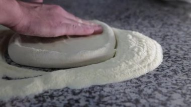 Şef mermer masada pizza hamuru hazırlıyor.