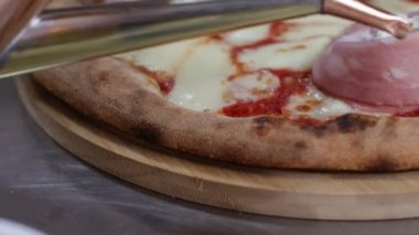 Mortadella gülleri, mozzarella peyniri ve domates soslu pizzaya yağ ekliyorum.