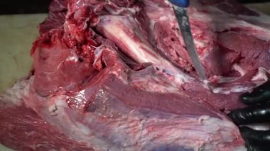 Kasap, büyük bir parça kırmızı etten kemikleri ayırıyor.