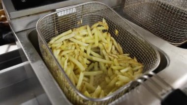 Profesyonel bir fritözün içinde kızgın yağda kızartılmış patates kızartması.