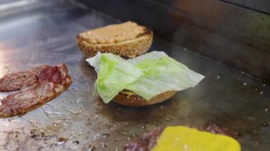 Pastırmalı, peynirli ve salatalı bir hamburger pişir.