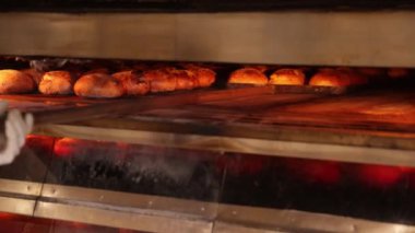 Baker endüstriyel fırından altın kahverengi ekmeği çıkarıyor