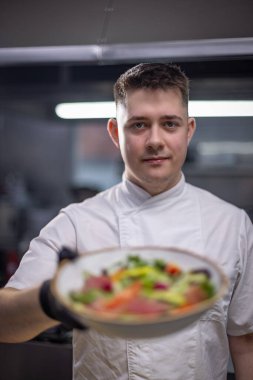 Şef restoran mutfağında gurme salatası tutuyor.