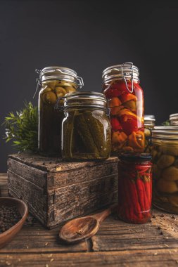 Kavanozlar dolusu salatalık, biber, domates ve biber kırsal ahşap bir kutuda düzenlenir.