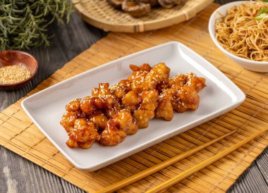 Beyaz tabakta bal soslu susamlı tavuk servis ediliyor.