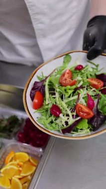 Profesyonel bir aşçı, ticari bir mutfakta sağlıklı ve taze malzemeli bir salata hazırlıyor.