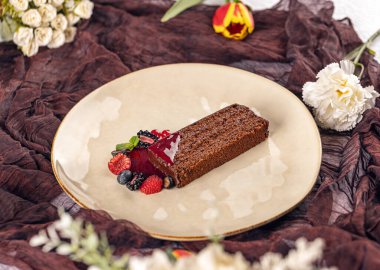 Çilekli pasta dilimi ve zarif tabakta taze meyveler.