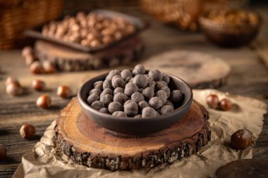 Çikolata kaplı fındıklar, tahta bir standın üzerinde kakao tozuyla bir kasede sergilenir.