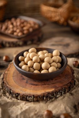 Beyaz çikolatayla kaplanmış, kavrulmuş fındıklı fındıklar, kırsal bir kasede servis edilir, lezzetli ve lezzetli bir atıştırmalık yaratır.