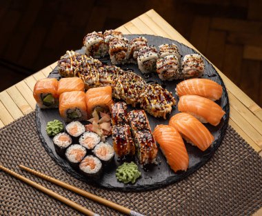 Soya sosu, zencefil turşusu ve wasabi ile servis edilen farklı rulo ekmeklerle lezzetli suşi karışımı.