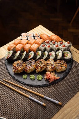 Çeşitli dürümlü suşi tabağı, nigiri ve wasabi yemek çubuklarıyla sergilenir.