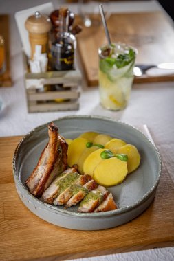 Dilimlenmiş domuz pirzolası, yanında patates ve pesto sosu.