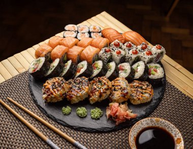 Çeşitli suşiler, çeşitli rulo, nigiri ve wasabi çeşitleri sergilenen bir sofra tabağında servis edilir.