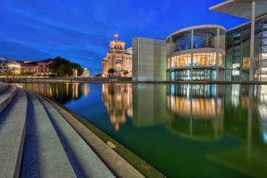 Paul-Loebe-Haus nehir kıyısında Alacakaranlıkta Berlin 'de Spree' de arkada Reichstag ile
