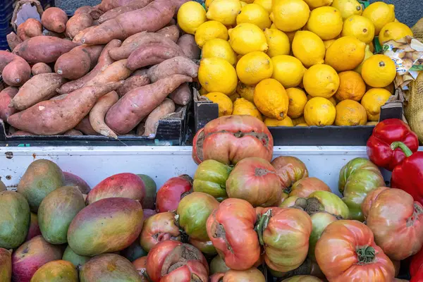 Bir markette satılık mango, domates ve diğer meyve ve sebzeler