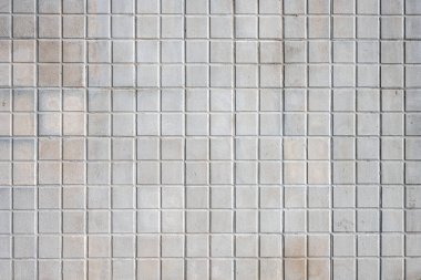 Background from a wall made of square beige mosaic tiles