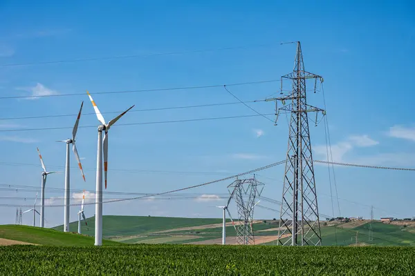 Stock image Electricity pylons with power lines and wind turbines seen in Puglia, Italy