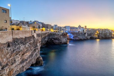Polignano ve Mare evleri gün batımından sonra uçurumun kenarında.