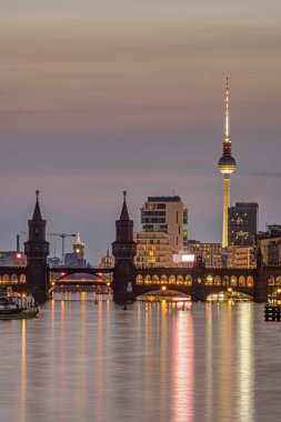 Berlin ve nehir. Alacakaranlıkta Spree Oberbaum Köprüsü ve ünlü Televizyon Kulesi.