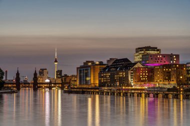 Berlin 'deki Oberbaum Köprüsü ve TV Kulesi. Alacakaranlıkta Spree nehri.