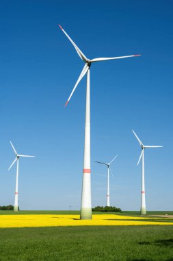 Almanya 'da görülen açık mavi gökyüzünün önündeki rüzgar türbinleri