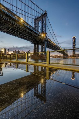 Günbatımında New York 'taki Manhattan Köprüsü bir su birikintisine yansıdı.