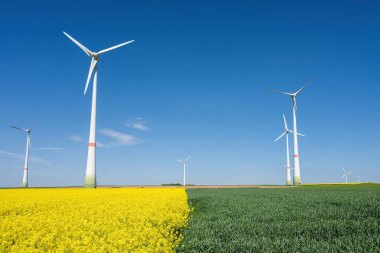 Wind turbines with green and yellow fields seen in Germany clipart