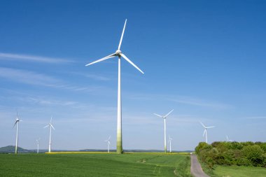 Modern wind energy plants with green fields seen in Germany clipart