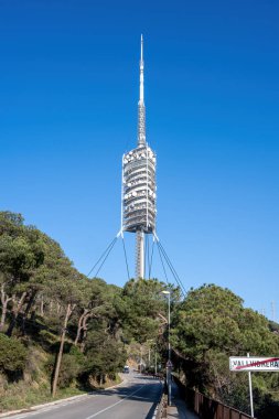 Barcelona, İspanya 'daki Torre de Collserola telekomünikasyon kulesi, mavi gökyüzünün önünde.