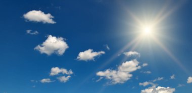 Bright sun on beautiful blue sky with white fluffy clouds.