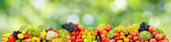 Fresh healthy vegetables, fruits, berries on green blurred background.