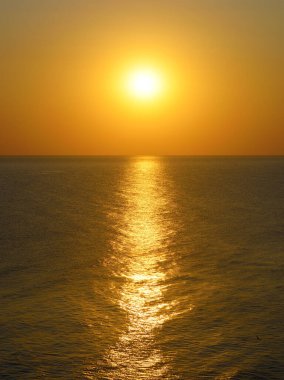 Turuncu gün batımı ve deniz yüzeyinde güneş yolu..