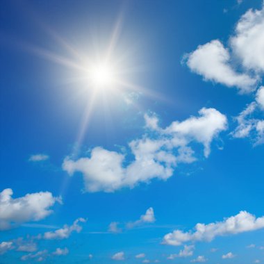 Bright sun on beautiful blue sky with white fluffy clouds.