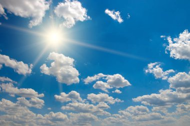 Parlak güneş güzel mavi gökyüzünde beyaz kabarık bulutlarla.