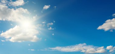 Parlak güneş güzel mavi gökyüzünde beyaz kabarık bulutlarla.