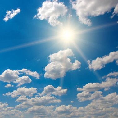 Parlak güneş güzel mavi gökyüzünde beyaz kabarık bulutlarla.