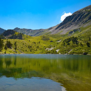 Dağların tepesinde, parlak mavi gökyüzünün arka planına karşı resim gibi bir göl..