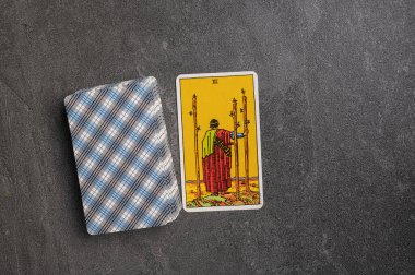 9 Kasım 2022 Ukrayna, Kyiv. Ryder 'ın Tarot' u... Asa takımının Junior Arcana 'sı. Üç, üç, üç. Gri taşlı arka planda fal bakımı için özel tarot kartları