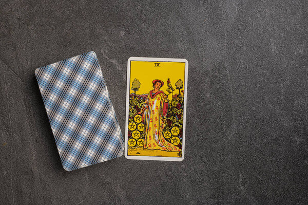 November 9, 2022 - Ukraine, Kyiv. Ryder's Tarot - Waite. The Minor Arcana of the suit of pentacles. Nine, IX, 9. Esoteric tarot cards for fortune telling on a gray stone background