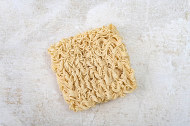 Açık bej taştan mermer bir arka planda brikette kare kuru yumurtalı erişte. Asya fast food.