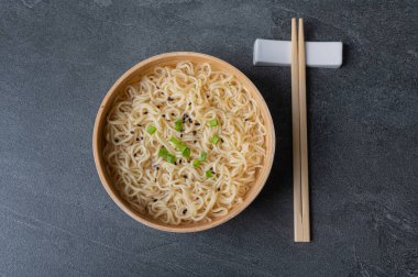 Beyaz bambu tabağı (kase) yumurta eriştesi ve siyah mermer (tahta) arka planda çubuklar ile. Asya geleneksel fast food