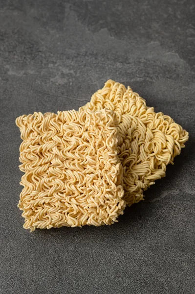 Square dry egg noodles in a briquette on a gray stone marble (slate) background. Asian fast food.