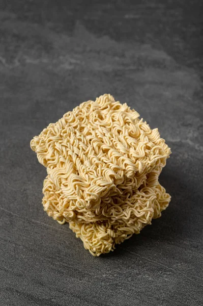 stock image Square dry egg noodles in a briquette on a gray stone marble (slate) background. Asian fast food.