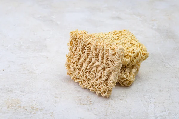 stock image Square dry egg noodles in a briquette on a light beige stone marble background. Asian fast food.