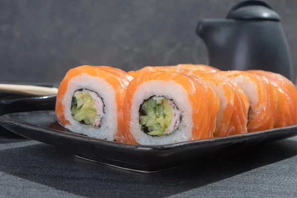 Rollos Sushi Con Salmón Aguacate Pepino Sobre Plato Rectangular Negro — Foto de Stock