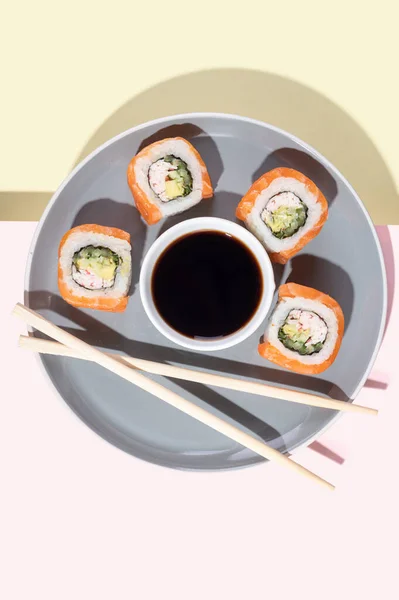 日本寿司与鲑鱼 龙滚动在明亮的黄粉色背景 流行艺术 用灰色盘子和筷子做的小吃味道不错 亚洲传统食品J — 图库照片